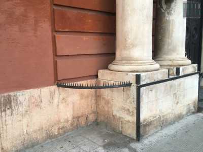 Accanto a Palazzo di Cagno Abbrescia (tra piazza Massari e corso Vittorio Emanuele), Appoggiata allo stilobate sinistro in pietra che regge le due colonne che abbelliscono il portone di legno, si trova una recinzione in ferro appuntita e semi circolare